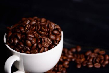 Kahve çekirdekleri ve beyaz bardak siyah deri arka planda izole edilmiş..