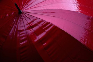 Kırmızı şemsiye yağmuru ve sağlığa zararlı rüzgarı önler.