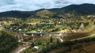 dağlar ve köyler arasında eski köprü viyadüğü üzerinde tren sürmek havadan drone görünümü