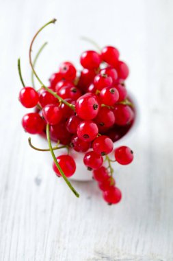 ahşap yüzeyde bir kase kırmızı kuş üzümü