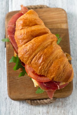 argugula, jamon, peynir ve domates ahşap yüzeyde kruvasan