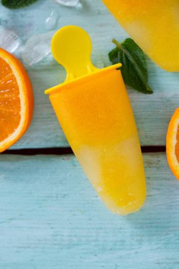 Ev yapımı turuncu çubuklu dondurmayı turkuaz ahşap yüzey üzerinde