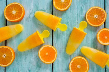 Ev yapımı turuncu çubuklu dondurmayı turkuaz ahşap yüzey üzerinde