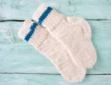 Turkuaz ahşap yüzeyde beyaz örülmüş çoraplar.