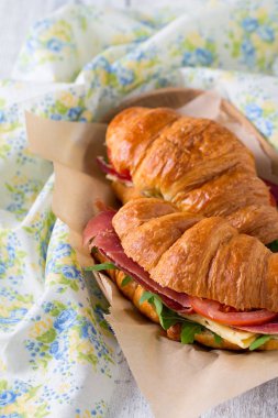 argugula, jamon, peynir ve domates ahşap yüzeyde kruvasan