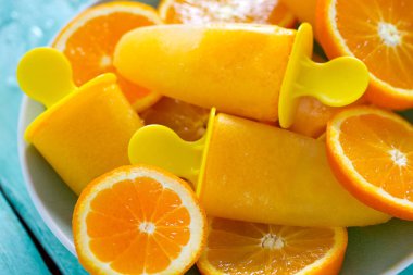 Ev yapımı turuncu çubuklu dondurmayı turkuaz ahşap yüzey üzerinde