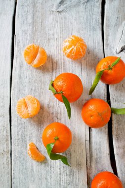 Turkuaz ahşap arka planda yeşil yapraklı mandalinalar