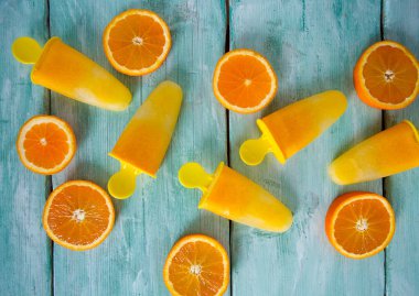 Ev yapımı turuncu çubuklu dondurmayı turkuaz ahşap yüzey üzerinde