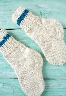 Turkuaz ahşap yüzeyde beyaz örülmüş çoraplar.