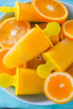 Ev yapımı turuncu çubuklu dondurmayı turkuaz ahşap yüzey üzerinde