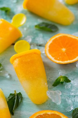 Ev yapımı turuncu çubuklu dondurmayı turkuaz ahşap yüzey üzerinde