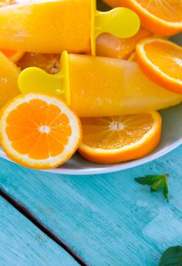 Ev yapımı turuncu çubuklu dondurmayı turkuaz ahşap yüzey üzerinde