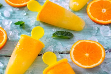 Ev yapımı turuncu çubuklu dondurmayı turkuaz ahşap yüzey üzerinde