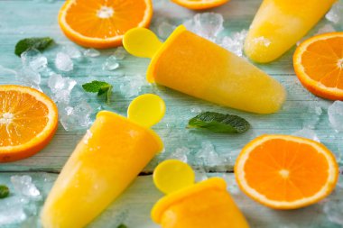 Ev yapımı turuncu çubuklu dondurmayı turkuaz ahşap yüzey üzerinde