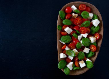 Koyu ahşap yüzeyde Caprese salatası