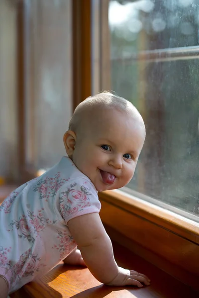 Słodkie Dziecko Pokazuje Jej Język Obok Okna — Zdjęcie stockowe