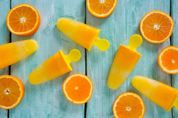 Ev yapımı turuncu çubuklu dondurmayı turkuaz ahşap yüzey üzerinde