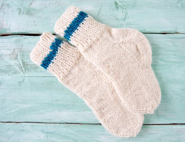 Turkuaz ahşap yüzeyde beyaz örülmüş çoraplar.