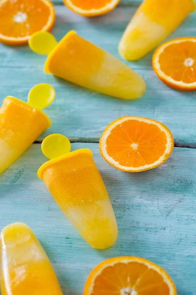 Ev yapımı turuncu çubuklu dondurmayı turkuaz ahşap yüzey üzerinde