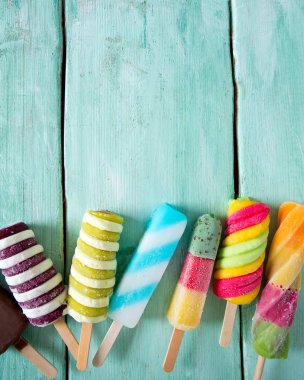 Turkuaz ahşap arka plan üzerinde renkli buzlu çubuk dondurma