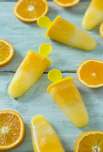 home made orange popsicles on turquoise wooden surface