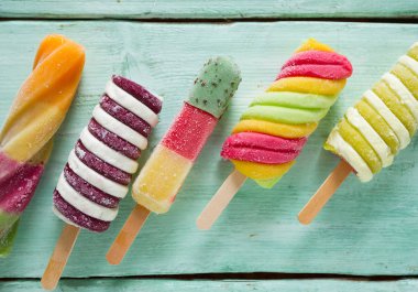Turkuaz ahşap arka plan üzerinde renkli buzlu çubuk dondurma