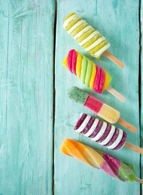 Turkuaz ahşap arka plan üzerinde renkli buzlu çubuk dondurma