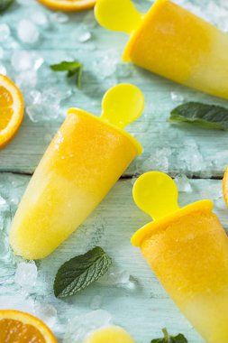 Ev yapımı turuncu çubuklu dondurmayı turkuaz ahşap yüzey üzerinde