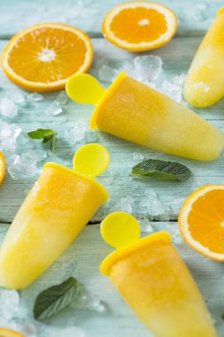 Ev yapımı turuncu çubuklu dondurmayı turkuaz ahşap yüzey üzerinde