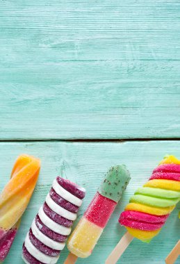 Turkuaz ahşap arka plan üzerinde renkli buzlu çubuk dondurma