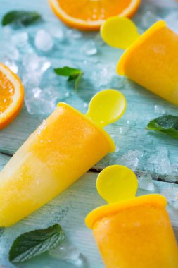 Ev yapımı turuncu çubuklu dondurmayı turkuaz ahşap yüzey üzerinde