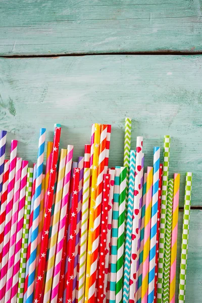 multicolored paper straws on turquoise wooden background