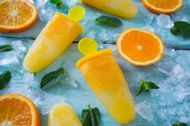 Ev yapımı turuncu çubuklu dondurmayı turkuaz ahşap yüzey üzerinde