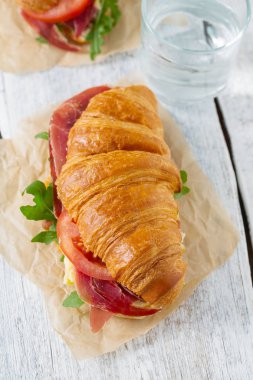 argugula, jamon, peynir ve domates ahşap yüzeyde kruvasan