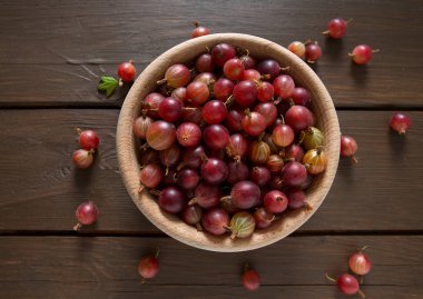 Ahşap yüzeyde bir kasede kırmızı bektaşi üzümü
