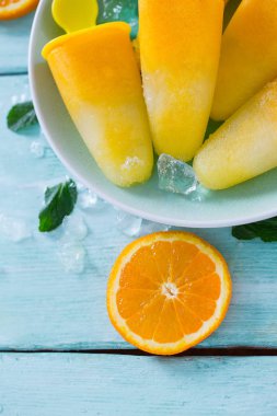 Ev yapımı turuncu çubuklu dondurmayı turkuaz ahşap yüzey üzerinde