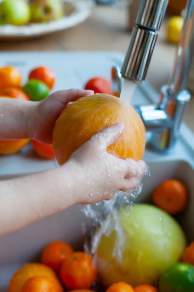 cute boy is washing citrus fruits