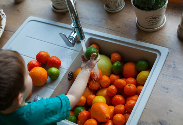 cute boy is washing citrus fruits