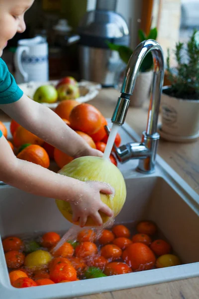 cute boy is washing citrus fruits