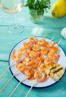 Ahşap yüzeyde ızgara karides şişleri.