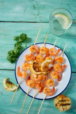 Ahşap yüzeyde ızgara karides şişleri.