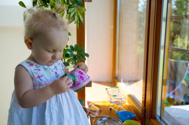 Şirin küçük kız oyuncak bardağından çay içiyormuş gibi yapıyor.