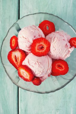 Turkuaz bir yüzeyde çilekli dondurma.