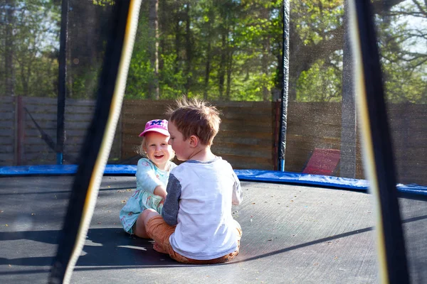 Lindos hermanos sentados en un trampolín en un día de primavera —  Fotos de Stock