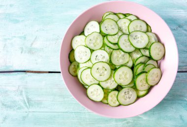 Turkuaz yüzeyinde bir kasede salatalıklar.