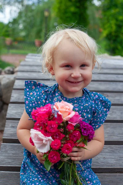 Menina loira bonito está segurando um buquê de flores — Fotografia de Stock