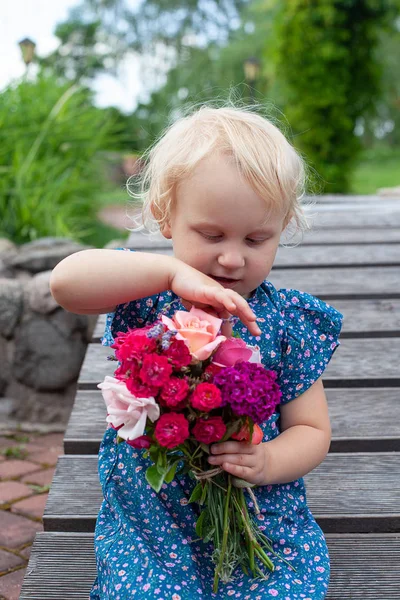 Menina loira bonito está segurando um buquê de flores — Fotografia de Stock