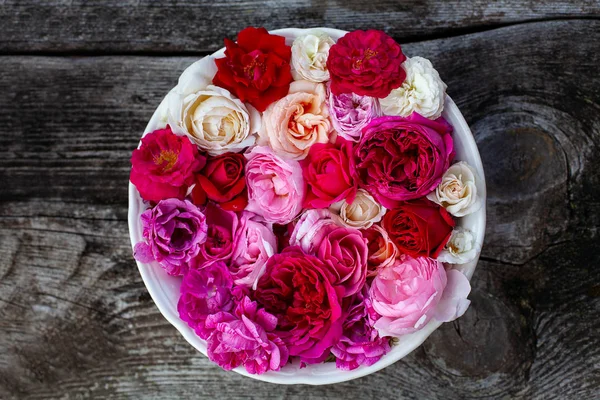Różowe, czerwone, fioletowe i białe róże na powierzchni drewnianej — Zdjęcie stockowe
