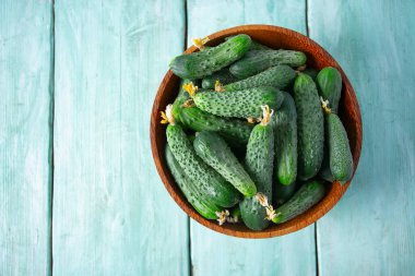 Ahşap yüzeydeki bir kasede salatalıklar.