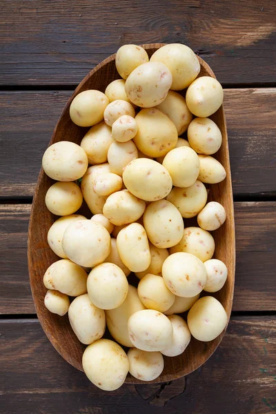 Nowe ziemniaki na brązowej powierzchni drewnianej — Zdjęcie stockowe